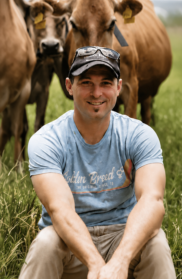 Aaron Thomas, dairy farmer in Gippsland, sitting in pasture with his Jersey cows