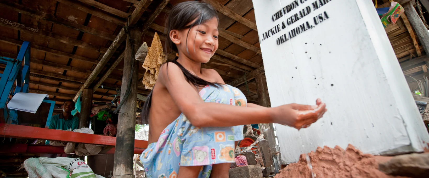 Young Cambodian girl washing hands with clean water from a community well funded through B1G1 giving